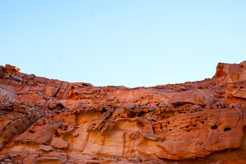 a beautiful view of a mountain desert canyon of red color against the background of a blue sky and a scorching sun