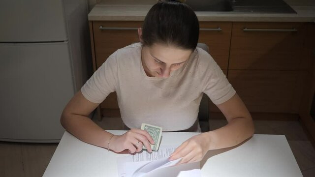 Stressed woman having financial problems sitting on kitchen and reading tax notification document. Concept of financial difficulties, bankruptcy, taxes and rent payment.