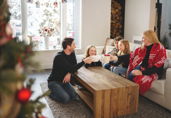 Family Enjoying Hot Drink In Cafe at home close to fireplace