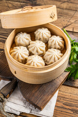 Fototapeta na wymiar Momo dumplings in a bamboo steamer. Wooden background. Top view