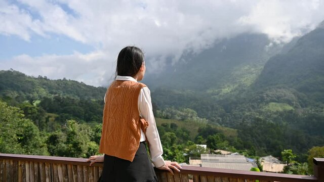 Beautiful asian woman standing and enjoying the mountain view on balcony at Chiang Dao