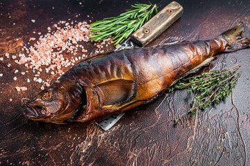 Hot smoked fish  walleye or pike perch on a wooden board with herbs. Dark background. Top view