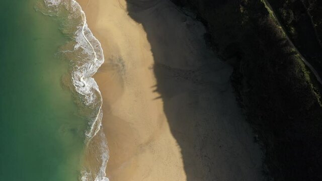 Evening light on a golden sand beach and green sea in Cornwall, UK