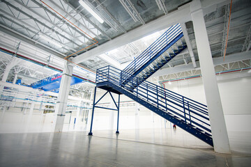 escaleras de metal color gris, azules en nave industrial, render