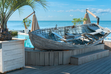 old fishing boat on a wooden pedestal on the sunny embankment of the Russian resort town of Sochi, Russia