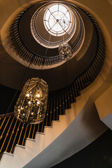 Counterpicture of a spiral staircase with two large lamps in gold and brown tones.