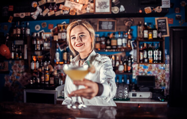 Girl bartender makes a cocktail in the pothouse