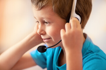 Naklejka premium Boy with headphones listens to online lessons. E-learning at home concept. 