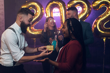 Happy beautiful couple celebrate New Year's Eve and exchanging gifts