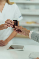 Obraz na płótnie Canvas Pharmacist hands selling medications to a senior customer in a pharmacy