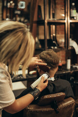 Young bearded man getting haircut by hairdresser