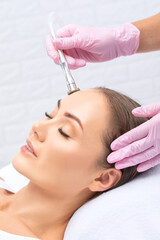 Obraz na płótnie Canvas The cosmetologist makes the procedure Microdermabrasion of the face skin of a beautiful girl in a beauty salon.Cosmetology and professional skin care.