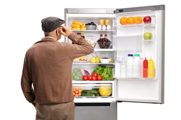 Rear view shot of an elderly man looking at an open fridge with food