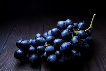 Fresh blue grapes on dark wooden background