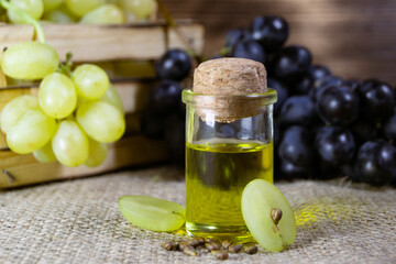 Grape oil seed in small vintage bottle. Heap of grape seeds with green slices and cold press organic essential oil, tincture, extract, infusion on wooden rustic background closeup