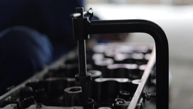 the hand of a mechanic is installing the valve seal of an overhauled car engine