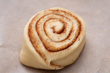 Raw cinnamon bun on baking paper. Cooking at home tasty buns with cinnamon powder