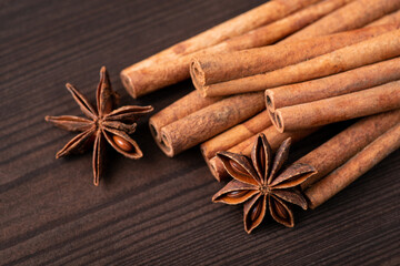 Close-up shot of cinnamon and some stars of anise against black wooden background. Cinnamon and star anise spices