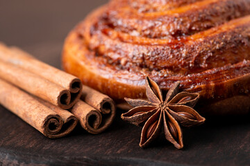 Beautiful composition of baked cinnamon bun with anise star and sticks of cinnamon. Cooking at home