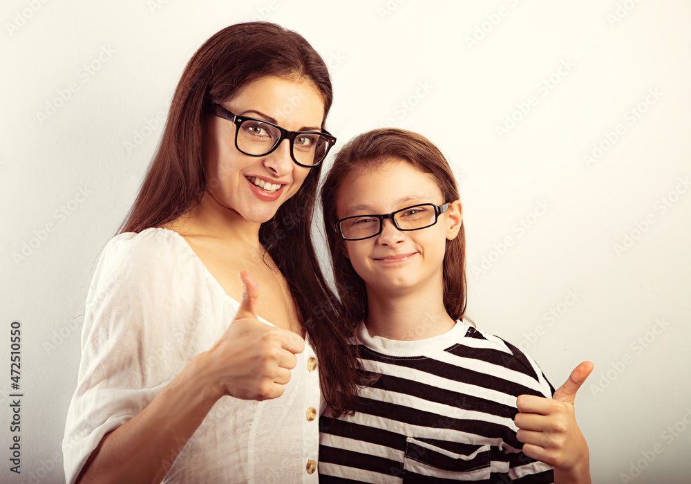 Wall mural happy young mother and lauging kid in fashion glasses hugging and showing thumb up on empty copy spa