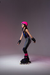 young skater athlete with pink helmet and protective gear training for competition in a studio.