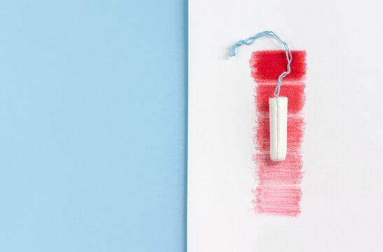 Feminine hygiene tampon and red rectangles on white and blue background. The concept of the intensity of blood flow during the menstrual cycle. Copy space