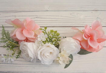 Light Coral and White Flowers with Green Leaves in Horizontal Row Across Bottom of Wood Planks with Room for Text