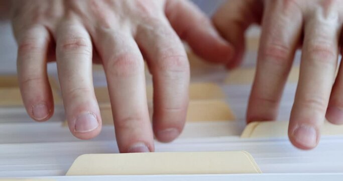 Male Hands Are Sorting Through Folders With Documents In Filing Cabinet