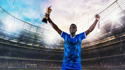 Fototapeta na wymiar Soccer player in blue uniform rejoices for the victory of a trophy at the stadium