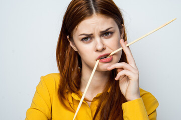 woman eating sushi with japanese chopsticks posing light background