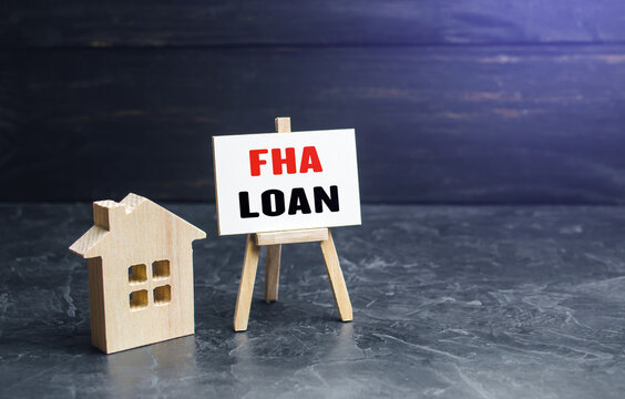 Small gouse and FHA loan easel sign. High risk of default. Mortgage insured by Federal Housing Administration Loan. An affordable financial instrument for borrowers with a low credit score.