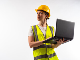 Woman in reflective vest and hard hat looks up. Girl engineer or builder. Engineer with laptop on a white background. Portrait of employee of an engineering bureau. Builder woman with computer.