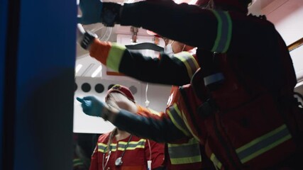 Low angle of medical practitioners in uniform and masks preparing equipment in hurry while taking care of patient in ambulance car during emergency at night