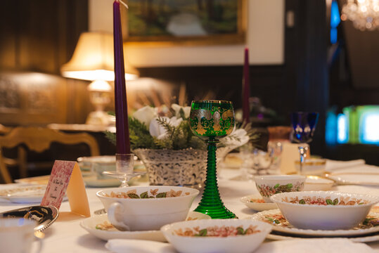 Holiday festive table setting, chine, cutlery, decorations, Christmas dinner scene with wine goblets
