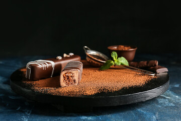 Board with tasty cocoa cakes on dark background