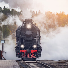 Obraz na płótnie Canvas Retro steam train arrives to the station wooden platform.