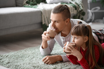 Happy daughter and father drinking hot cocoa at home