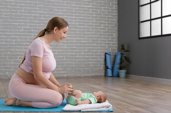 Young pregnant woman with little baby training at gym