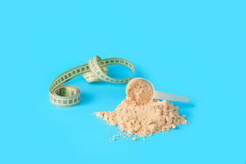 Scoop with protein powder and measuring tape on color background