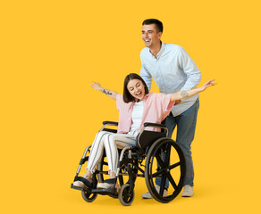 Young woman in wheelchair and her husband on color background