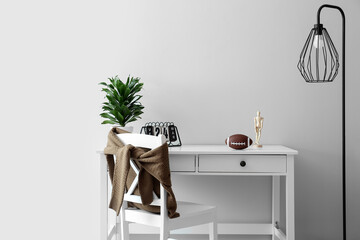 Modern workplace with rugby ball and lamp near white wall