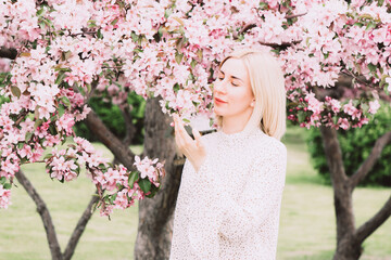 Young woman among the blossoming trees. Spring nature park or garden, flowering trees. Concept spring woman health