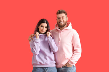 Naklejka premium Cool young couple in hoodies on color background
