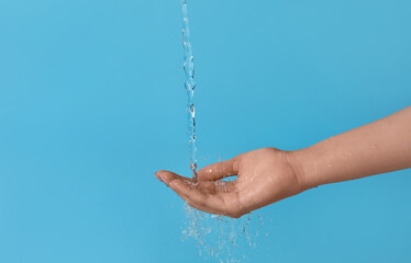 Female hand and pouring water on blue background