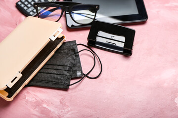 Medical masks with case, tablet computer and eyeglasses on color background