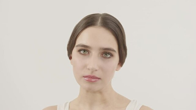 A beautiful girl with her hair gathered in a bundle lowers her eyes.