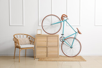 Modern bicycle with chest of drawers and chair near white wall