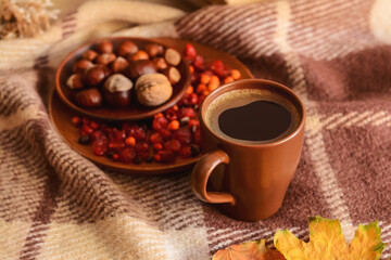 Brown cup of hot coffee on checkered fabric background, closeup