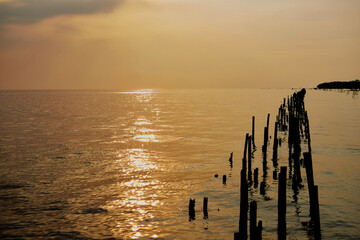 sunset over the sea with wooden post