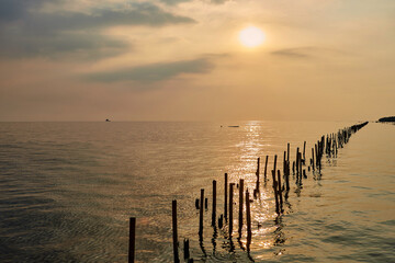 sunset over the sea with wooden post